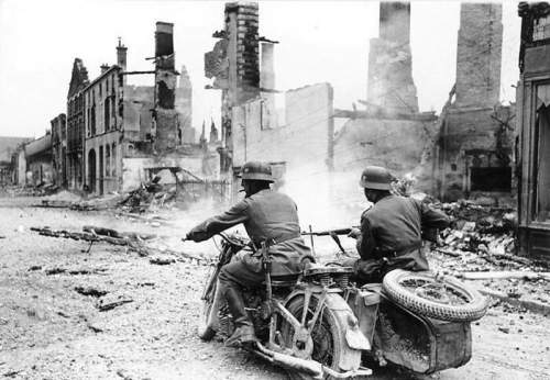 Нацистские мотоциклисты проезжают через разрушенный город во Франции в 1940 году.
