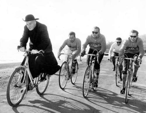 Местный священник резко разворачивается впереди и дает велосипедистам из Аталы передышку во время тренировочного забега в рамках подготовки к многодневной гонке Джиро Д'Италия 1959 года. Италия. Под Миланом, 1959 год.