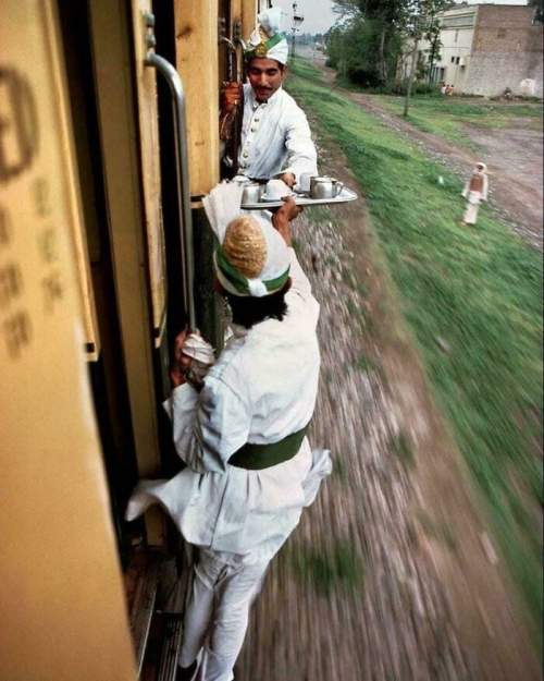 Завтрак с чаем передают между вагонами в поезде из Пешавара в Лахор, 1983 год. Снято Стивом Маккарри.
